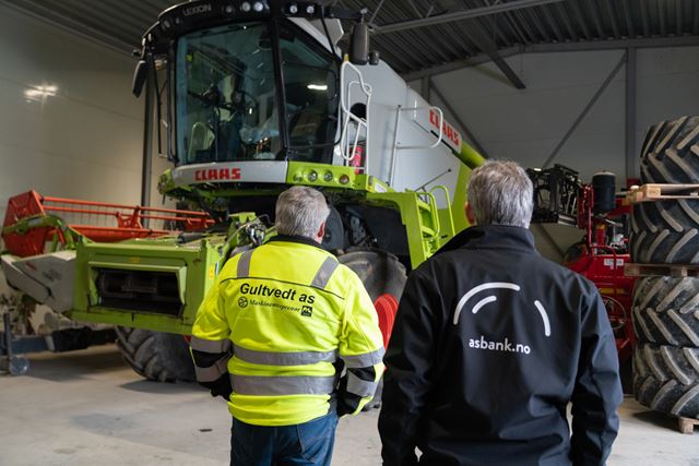 Ryggen til to menn som ser på en skurtrøsker